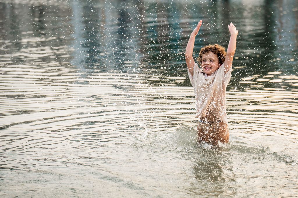 Natural family photoshoot in Mallorca with child playing in the water